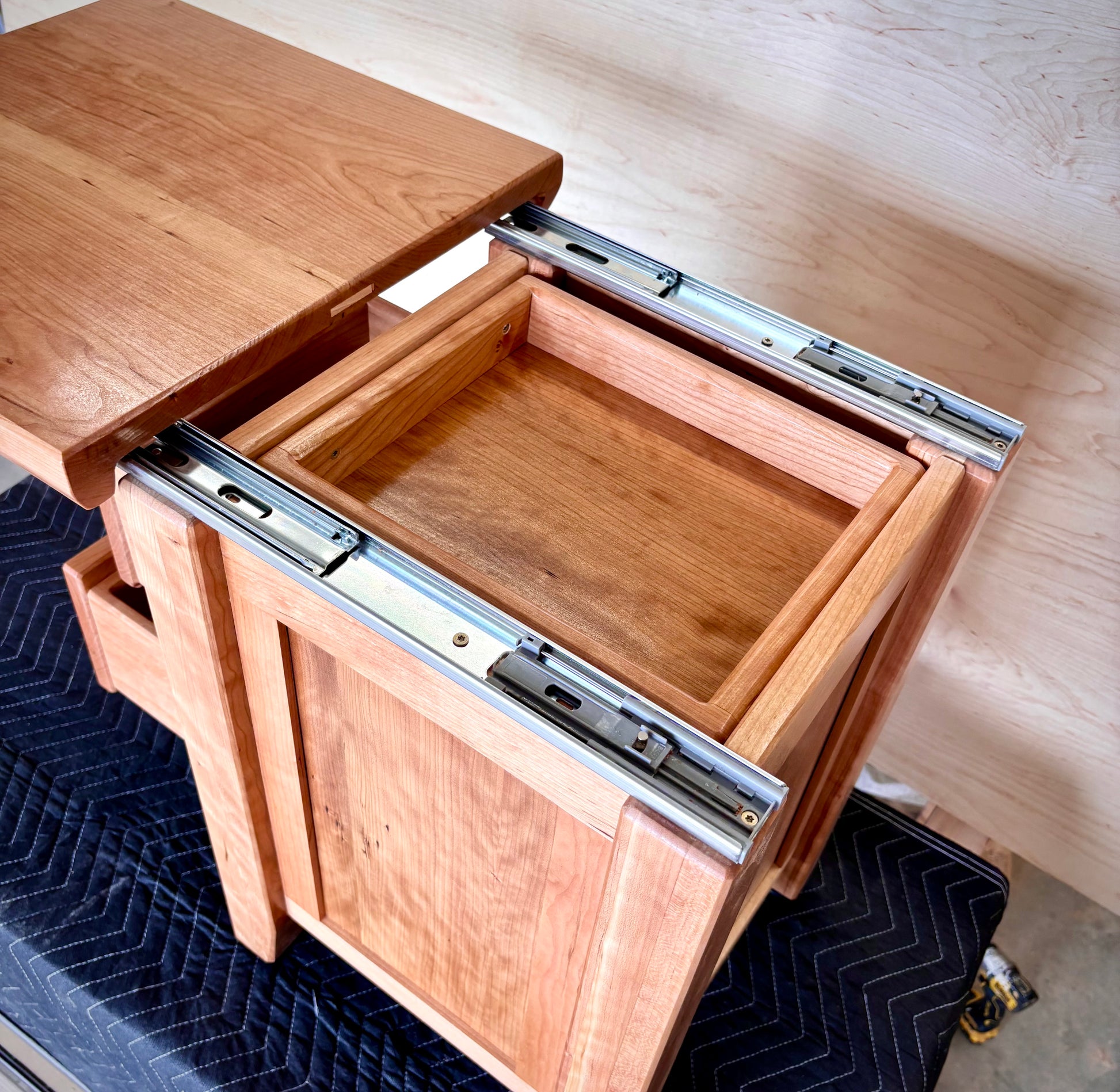 Handmade cherry nightstand with hidden storage open.